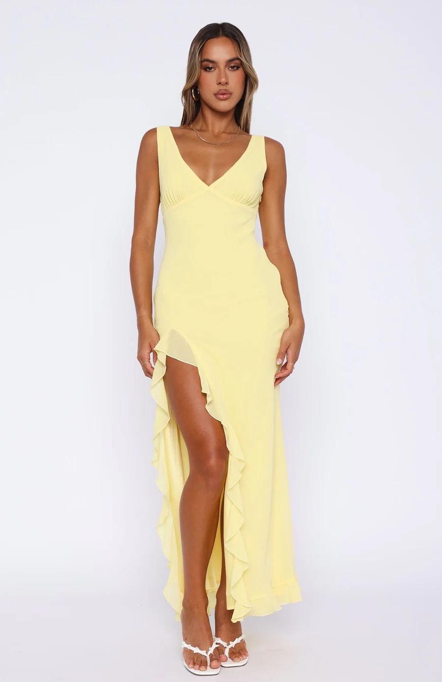 Woman wearing a yellow dress with a slit on a white background