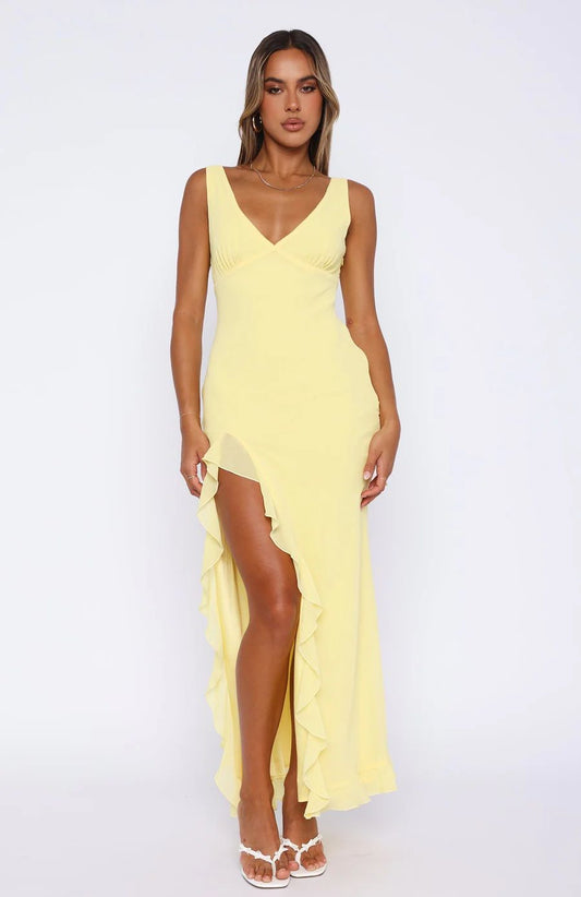 Woman wearing a yellow dress with a slit on a white background